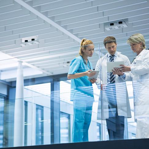 Trois professionnels de la santé discutent dans un couloir moderne