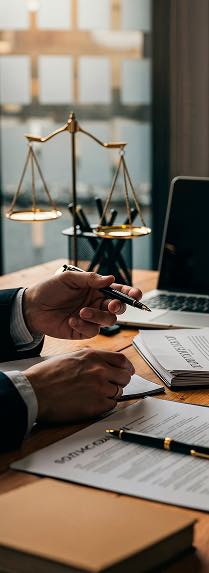 Mains d'avocat tenant un stylo au-dessus de documents dans un cabinet d'avocats affaires.