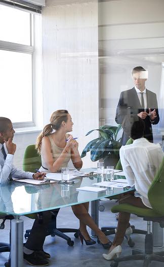 Équipe en réunion de management de projet AMO, discutant avec un présentateur.