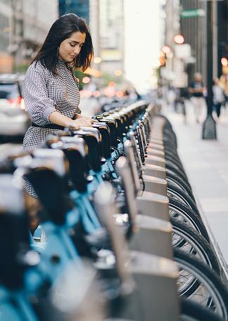 Femme consultant une station de vélos en libre-service à Paris, relevant de la stratégie du cabinet d'avocats affaires.